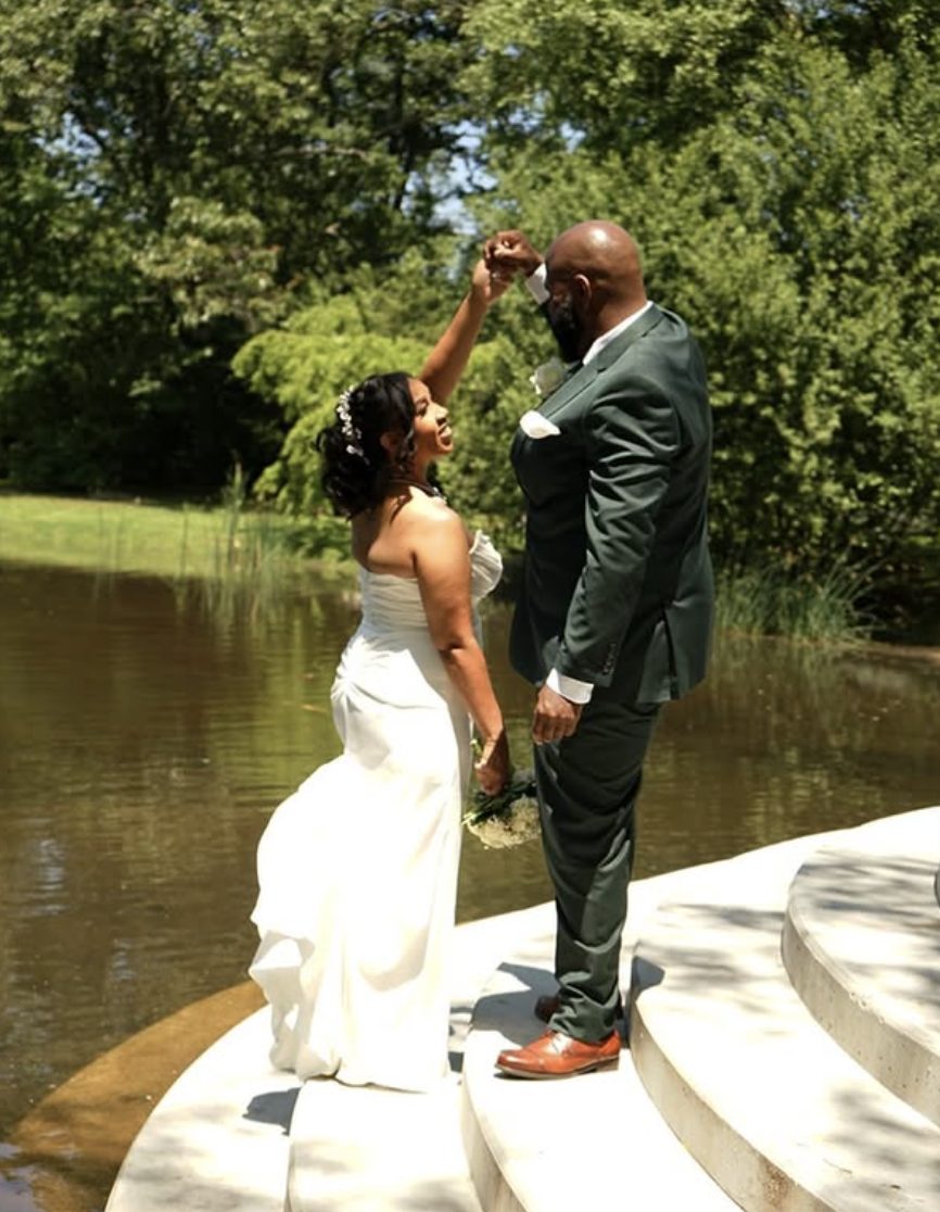 The groom twirls the bride on the temple steps at the water's edge.