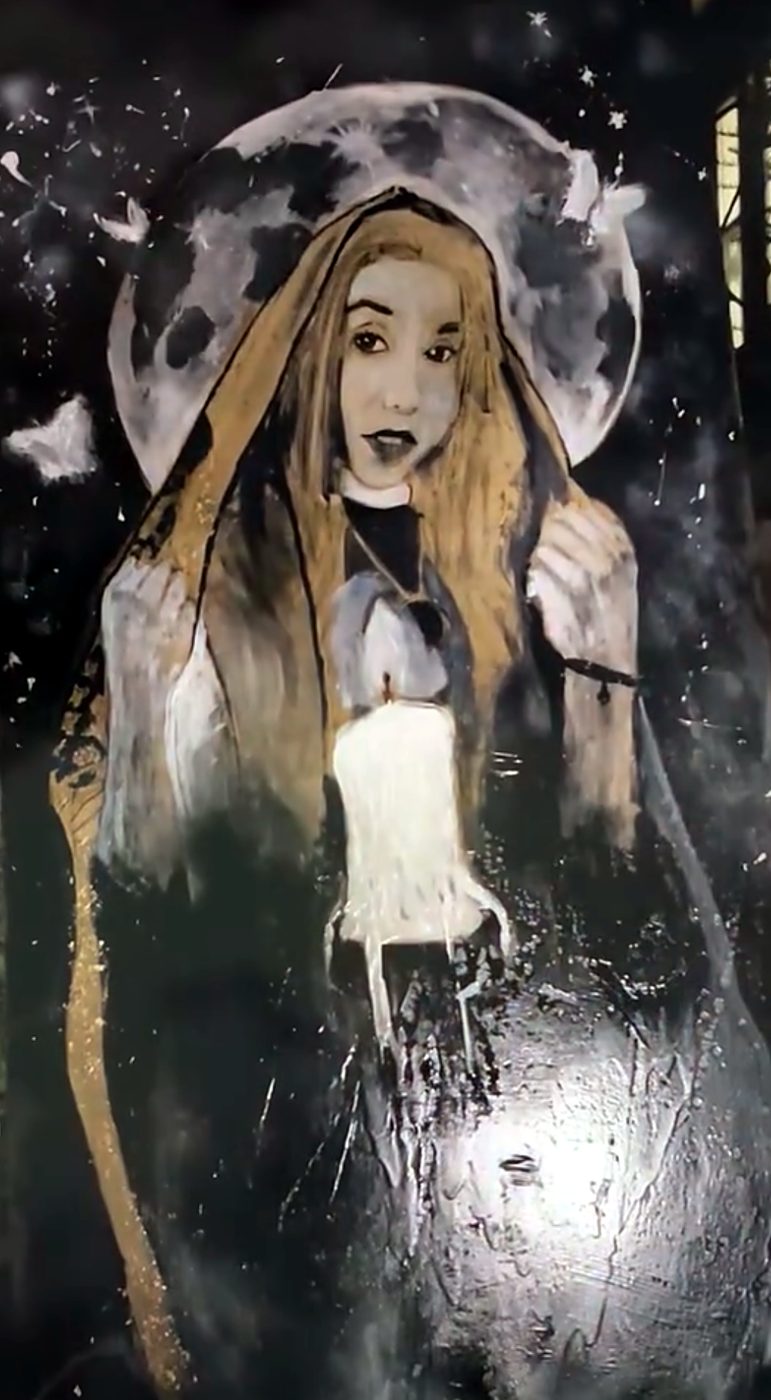 A priestess in a golden hooded robe holding a white candle, a full moon behind her head